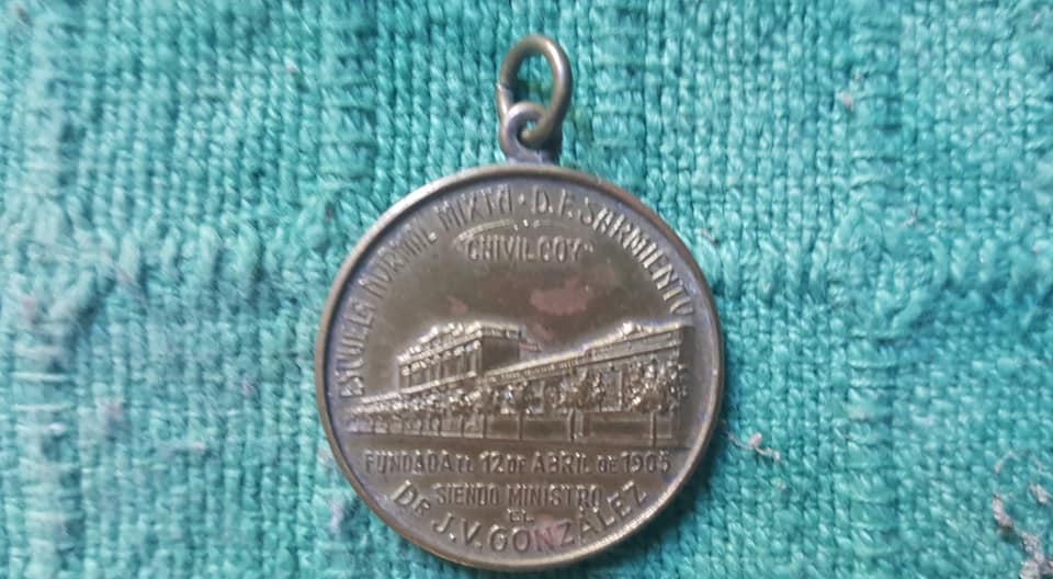 Una medalla conmemorativa, del XX  aniversario de la Escuela Normal “Domingo Faustino Sarmiento”, en 1925.